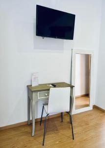 einen Schreibtisch mit Stuhl und einen TV an der Wand in der Unterkunft Guest house D. Filipe I in Porto