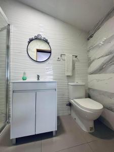 a white bathroom with a toilet and a mirror at Guest house D. Filipe I in Porto