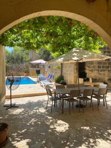 - une table et des chaises sous un parasol à côté de la piscine dans l'établissement Tal-Masklu farmhouse, à L-Għarb