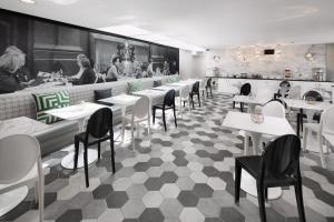 a restaurant with white tables and chairs and a kitchen at Carlyle Inn in Los Angeles