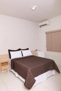 um quarto com uma cama grande num quarto branco em Hotel Borges em Quirinópolis