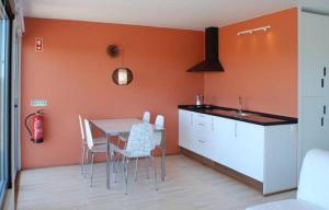 a kitchen with a table and chairs and an orange wall at Bubulcus and Bolotas - Off Grid Nature Holiday Home in Vimieiro