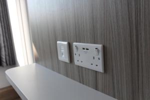 a white electrical outlet on a wooden wall at Sky Nights Hotel London Heathrow in Hillingdon