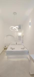 biały pokój z łóżkiem i żyrandolem w obiekcie Cozy Now w mieście Tinos