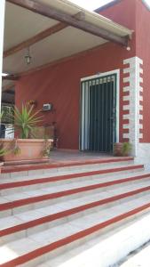 ein rotes Gebäude mit einer Treppe, die zu einer Tür führt in der Unterkunft Villetta Beatrice in Noto