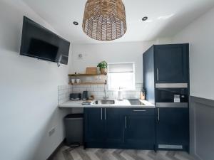 a kitchen with blue cabinets and a sink at Goodstay Lodges by Urban Space in Barry
