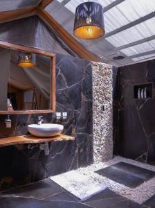 a bathroom with a sink and a stone wall at Sleeping Warrior Camp Elementaita in Nakuru +40 photos