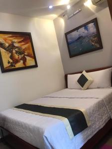 two beds in a room with paintings on the walls at Khách Sạn Blue Sky in Xã Thang Tam