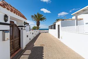 a pathway between white buildings with a palm tree in the background at 2BR Terrace Home - 10 min walk to the Beach in Playa Honda