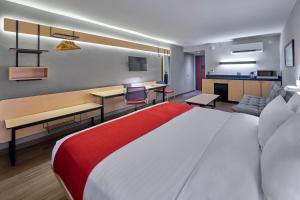 a hotel room with a large bed and a living room at City Express by Marriott Mérida in Mérida