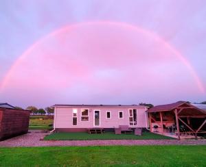 un arco iris sobre una casa rosa en un campo en Marduijn en Lomm
