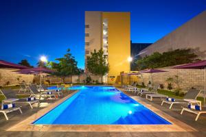 una piscina con sedie a sdraio e un edificio di City Express by Marriott Mérida a Mérida