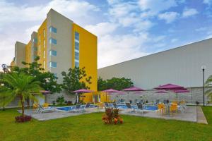 a building with tables and chairs and purple umbrellas at City Express by Marriott Mérida in Mérida
