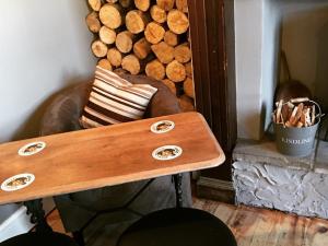 a wooden table in a room with a chair and a pile of logs at The Westmorland Inn in Bowness-on-Windermere