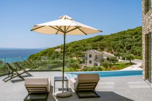 une terrasse avec 2 chaises, un parasol et une piscine dans l'établissement The View Hotel Sofas Coastal Retreat, à Perdika