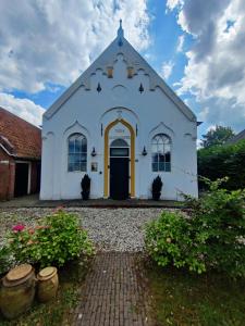 a white church with a yellow door and some plants at Kerkje De Kleine Antonius in Zeerijp
