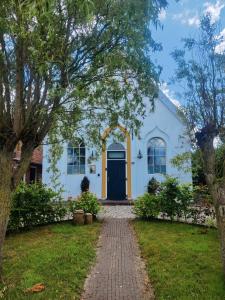 a white house with a blue door and a brick driveway at Kerkje De Kleine Antonius in Zeerijp