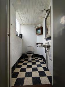 a bathroom with a toilet and a checkered floor at Kerkje De Kleine Antonius in Zeerijp