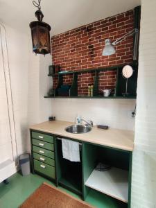 a kitchen with a sink and a brick wall at Kerkje De Kleine Antonius in Zeerijp