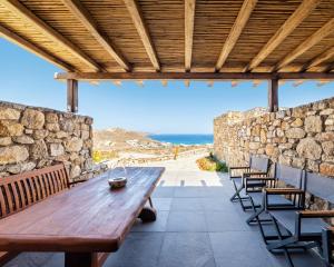 a wooden table and chairs on a patio with a view of the ocean at Villa Agavi - Private Pool & Security included - Ideal for events in Mikonos