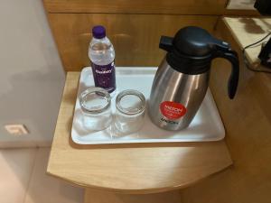 een dienblad met een koffiezetapparaat, 2 glazen en een fles water bij Hotel Ashirwad in Pune