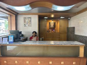 a woman sitting at a counter in an office at Hotel Ashirwad in Pune