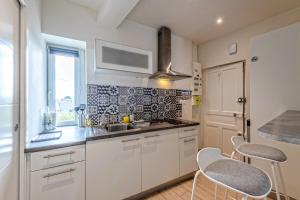 a kitchen with white cabinets and a sink and a window at Studio Christiane - en plein coeur de Roscoff in Roscoff +5 photos