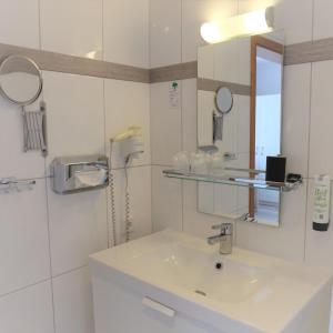 a white bathroom with a sink and a mirror at Hotel Strand26 in Nienhagen