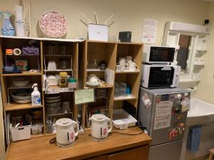 a kitchen with a counter with a microwave and a refrigerator at Tsukiji Hostel Wakayama 3 in Wakayama