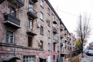 ein großes Backsteingebäude mit Balkonen an einer Stadtstraße in der Unterkunft hotelise I Sketch Apartment in Yerevan