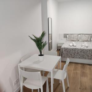 un comedor blanco con mesa, sillas y cama en Garcia Noblejas Apartments, en Madrid