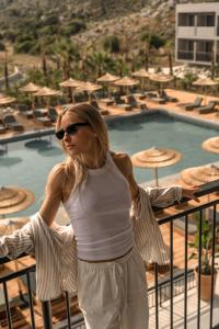 a woman standing on a balcony near a swimming pool at Cook's Club Kolymbia Rhodes -Adults only in Kolimbia