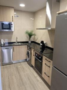 eine Küche mit einem Kühlschrank und einem Geschirrspüler in der Unterkunft San Sebastián Apartments in San Sebastián de los Reyes