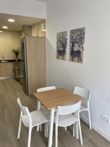 a dining room with a table and white chairs at San Sebastián Apartments in San Sebastián de los Reyes