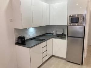 cocina con armarios blancos y nevera de acero inoxidable en Matadero Apartments 1 en Madrid