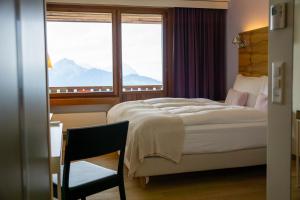 ein Schlafzimmer mit einem Bett, einem Stuhl und einem Fenster in der Unterkunft Wellness Hotel Stoos in Stoos