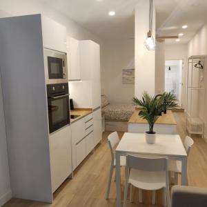 una cocina con armarios blancos y una mesa con una maceta. en AV. Asturias Apartamento, en Madrid