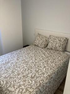 1 cama con 2 almohadas y edredón gris y blanco en Plaza Castilla Apartments en Madrid