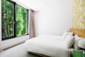 1 dormitorio con cama blanca y ventana grande en AMO 54 by Hakuba Hotel Group, en Hakuba