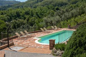 uma piscina com espreguiçadeiras e uma montanha em Casale della Visitazione by VacaVilla em Cantagrillo