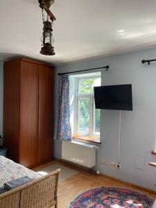Schlafzimmer mit einem Bett, einem Fenster und einem TV in der Unterkunft Lindenhof ChezArtistes in Loose