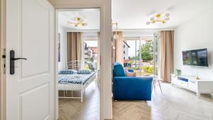 een woonkamer met een blauwe stoel en een eetkamer bij Baltic Garden Sztutowo Apartamenty PIAMOLA in Sztutowo