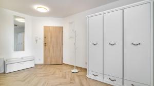 a bedroom with white cabinets and a wooden floor at Baltic Garden Sztutowo Apartamenty PIAMOLA in Sztutowo +24 photos
