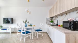 a kitchen with white cabinets and a table with chairs at Baltic Garden Sztutowo Apartamenty PIAMOLA in Sztutowo