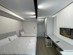 biały pokój z 2 łóżkami i telewizorem w obiekcie Vila Kapllani Rooms w Durrës