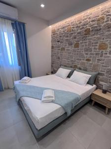 1 dormitorio con 1 cama grande y pared de ladrillo en Zeus & Emmanuil Luxury Houses, en Mirina
