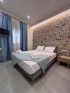 1 dormitorio con cama y pared de ladrillo en Zeus & Emmanuil Luxury Houses, en Mirina