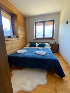 a bedroom with a blue bed with two towels on it at Apartament Zakopane Kościelisko in Kościelisko