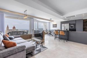 a living room with a couch and a kitchen at Dome Sunset Views Apartment in Mellieħa