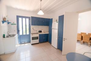 cocina con armarios azules y nevera blanca en Cottage on the Sea en Ítaca